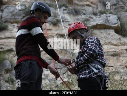 Hebron. 5 marzo 2021. Una donna palestinese (R) prepara le sue attrezzature per fare un rappel lungo una ripida scogliera nella riserva naturale di Wadi al-Qaf, nella città di Hebron, in Cisgiordania, il 5 marzo 2021. Contrariamente a quanto è comune nella loro società, un gruppo di giovani donne palestinesi partecipa a un rapimento dalle pericolose scogliere della Cisgiordania. Credit: Mamoun Wazwaz/Xinhua/Alamy Live News Foto Stock