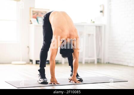 Giovane asiatico muscolare facendo esercizi sul pavimento a casa Foto Stock