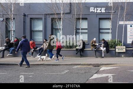 Persone che mangiano per strada dopo aver visitato Queen's Park Farmers mercato Foto Stock