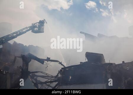 Disastro tecnologico, incendio, edificio industriale distrutto, fumo, estinzione incendi Foto Stock