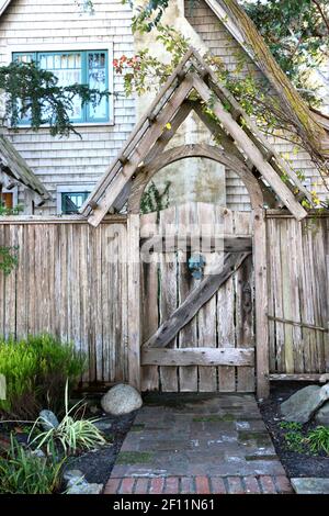 Questo caratteristico cancello di legno intemperie crea un'entrata stravagante al giardino di una casa con travi di cedro. Il design DEL telaio A rispecchia l'architettura di Foto Stock