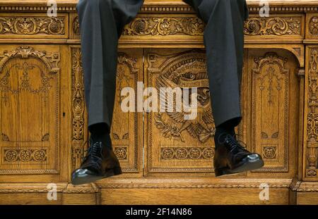 Le gambe del presidente Obama si sono arenate mentre siede sul Resolute Desk, mentre parla con due aiuti nell'ufficio ovale ca. 1° ottobre 2015 Foto Stock