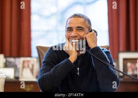 Un presidente sorridente Barack Obama fa il giorno del Ringraziamento telefonate alle truppe degli Stati Uniti, dall'Ufficio ovale, 27 novembre 2014. Foto Stock