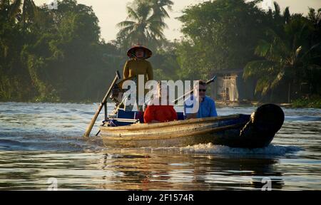 Coppia occidentale che viaggia su una canoa di legno tra il mercato galleggiante di prima mattina a Phong Điền, a quello di Cai Rang. Delta del Mekong, Vietnam Foto Stock