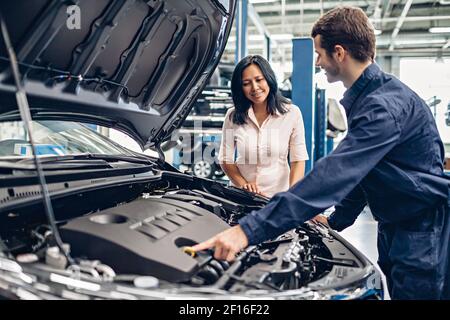 Scena del centro di assistenza auto. Il meccanico comunica con il cliente Foto Stock