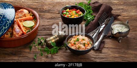 Stufato di pollo tagino con riso e verdure serviti con salsa e insalata. Concetto di pranzo orientale. Foto Stock