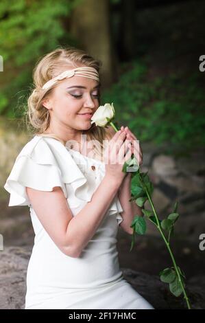 Bella ragazza sniffing rosa bianca Foto Stock