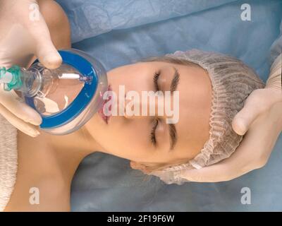 Primo piano - il medico dà l'anestesia al paziente prima di un intervento chirurgico o di una procedura di bellezza. Concetto di tecnologia medica moderna. Foto Stock