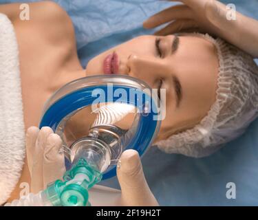 Primo piano - il medico dà l'anestesia al paziente prima di un intervento chirurgico o di una procedura di bellezza. Concetto di tecnologia medica moderna. Mettere a fuoco la maschera. Foto Stock