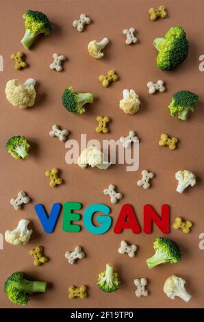 Modello di snack vegetariano cane e verdure sullo sfondo beige con scritta VEGAN. Foto Stock