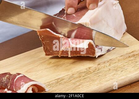 Prosciutto secco affettato a fette sottili Chiuseup su fette di mani dello chef Prosciutto alla gastronomia italiana Foto Stock