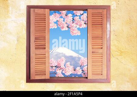 Vista del Monte Fuji (Fujiyama) e ramo della fiorente sakura attraverso la finestra con persiane in legno. Concetto di viaggio, vacanza e vacanza Foto Stock