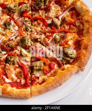 Fette di pizza di pollo al pesto su un piatto bianco con arrosto peperoni e cipolla rossa Foto Stock