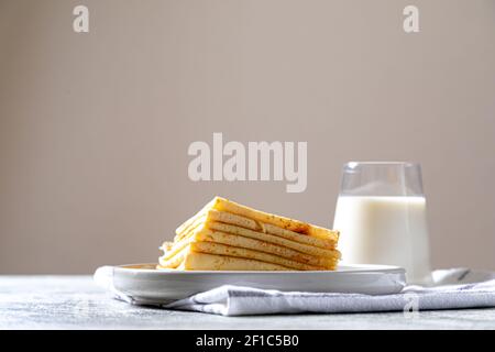 Crepes, pancake sottili su un piatto. comfor cibo, deliziosa colazione fatta in casa con frittelle dolci sottili e latte. Foto Stock