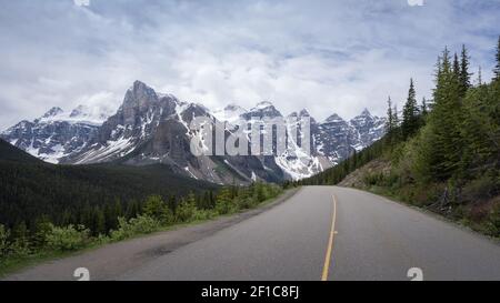 Strada asfaltata che conduce attraverso la splendida valle alpina, sparata in una giornata in cielo a Moraine Lake Road, Banff National Park, Alberta, Canada Foto Stock