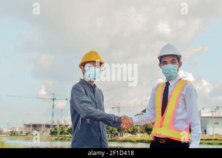 Uomo asiatico indossare maschera medica che tiene la tavoletta lavorando sul sito costruzione nuovo normale proteggere coronavirus covid 19 Foto Stock