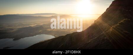 Sole che sorge sulla valle con il lago, girato durante l'alba sulla cima del Roys Peak a Wanaka, Nuova Zelanda Foto Stock