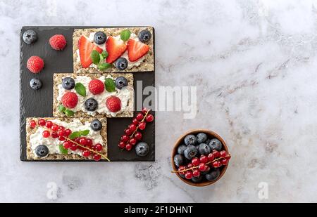 Frutta fresca d'estate snack sano di avena di segale croccante pane con frutti di bosco maturi, foglie di menta, e formaggio casolare Foto Stock
