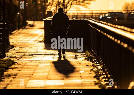 Uomo, anziano, camminando su un marciapiede, nel sole che tramonta, lunga ombra di getto, immagine simbolica, Essen, NRW, Germania Foto Stock