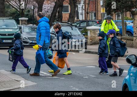 Londra, Regno Unito. 8 Marzo 2021. Le scuole della zona di Battersea riaprono alla prima fase dell'alleggerimento del Lockdowndue nazionale a Coronavirus (covid 19). I bambini sono chiaramente eccitati e la maggior parte dei genitori indossano maschere e mantengono la loro distanza. Credit: Guy Bell/Alamy Live News Foto Stock