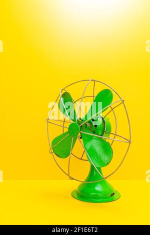 Vecchio ventilatore elettrico verde su sfondo giallo Foto Stock