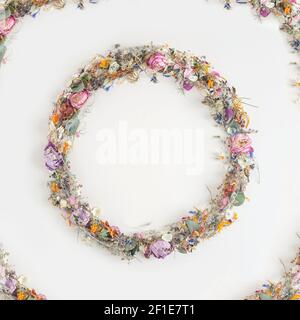 Cornice rotonda creativa realizzata con fiori naturali secchi estivi colorati, petali blu e foglie verdi su sfondo bianco. Concetto di vacanza minimo Foto Stock