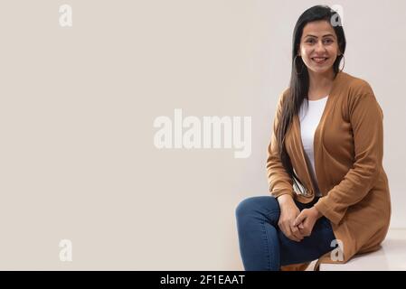 RITRATTO DI UNA DONNA ADULTA FELICEMENTE SEDUTA DI FRONTE FOTOCAMERA Foto Stock