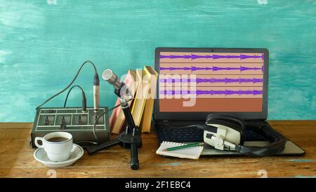 Registrazione di podcast o audiolibri con cuffie, microfono vintage, caffè e laptop su tavolo di legno Foto Stock