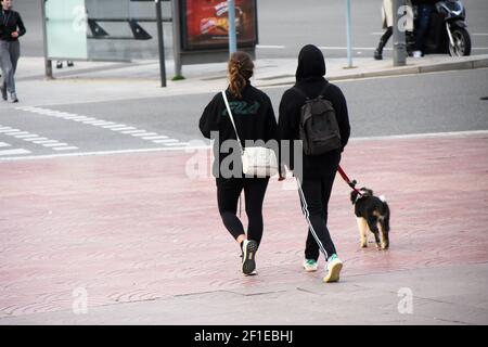 Vista posteriore di una coppia che cammina il cane in una strada. Persone reali, momento reale, vita reale. Foto Stock