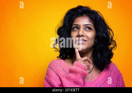 Bella Sri Lanka ragazza posa in piedi con giallo luminoso sfondo- La giovane donna sorride Foto Stock