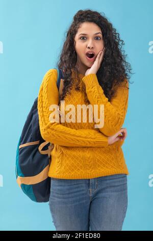 UNA RAGAZZA ADOLESCENTE IN PIEDI E TENERE BORSA GUARDANDO LA MACCHINA FOTOGRAFICA IN SHOCK Foto Stock