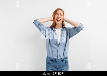 Ritratto di triste insoddisfatta donna aggressiva che ricopre le orecchie con palme su sfondo bianco Foto Stock