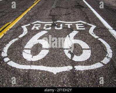 Lunga strada con un cartello della Route 66 dipinto su di essa Foto Stock