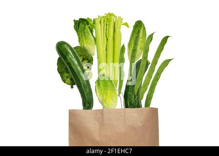 Verdure di colore verde che volano dalla borsa di carta di Kraft isolato su bianco Foto Stock