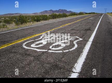 Lunga strada con un cartello della Route 66 dipinto su di essa Foto Stock