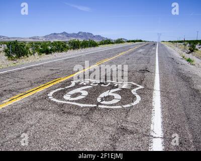 Lunga strada con un cartello della Route 66 dipinto su di essa Foto Stock