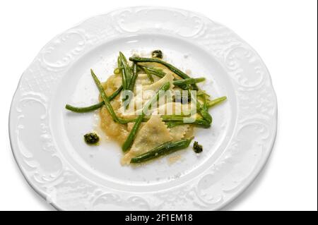 ravioli conditi con salsa al burro, parmigiano e fagioli verdi in piatto bianco isolato in vista dall'alto Foto Stock