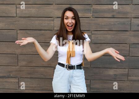 Foto di giovane emozionale felice allegra e allegra bruna attraente che indossa abiti eleganti in piedi per strada . Concetto di stile di vita Foto Stock