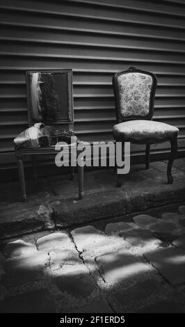Strappata poltrona rotta e restaurata. Rinnovamento, contrasti sociali, giovani e anziani, stili di vita diversi, concetti nuovi e vecchi. Mercato delle pulci backgro Foto Stock