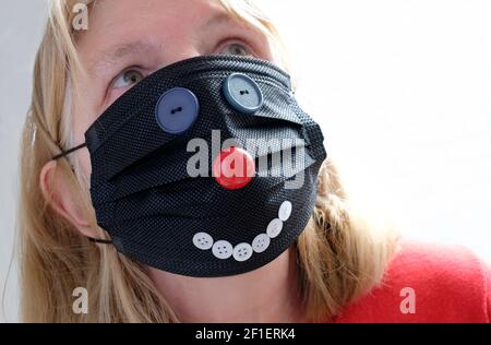 donna che indossa una faccia nera del coronavirus del giorno del naso rosso maschera Foto Stock