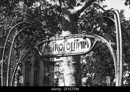 Cartello della metropolitana parigina su strada vuota in giornata di sole. Platani e tipico edificio di casa sullo sfondo. Parigi, Francia. Sfondo vintage. Vecchi tempi, Foto Stock