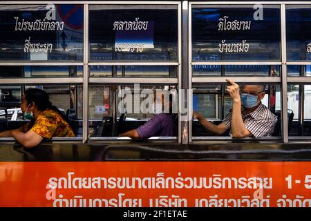 I passeggeri che indossano maschere durante il Covid 19 Pandemic si affacciano dalla finestra di un autobus di Bangkok a Chinatown, Bangkok, Thailandia Foto Stock