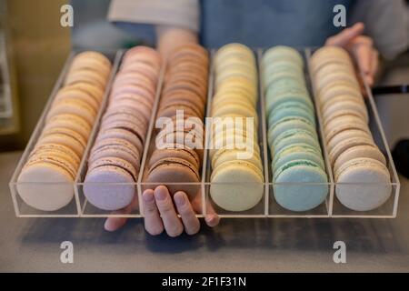 Molti macaron eclair colorato in vetrina di vetro al negozio di caramelle primo piano assortimento di biscotti per torte Foto Stock