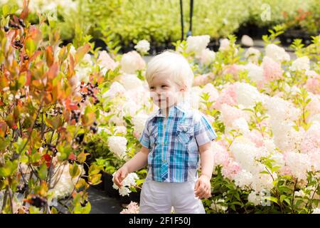 Bel ragazzo biondo all'aperto nel giardino botanico Foto Stock