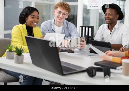 Team di colleghi creativi e multirazziali positivi che discutono i dettagli di progetto comune Foto Stock