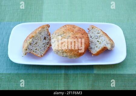 Due muffin di semi di papavero di limone su un piatto bianco, uno tagliato a metà Foto Stock