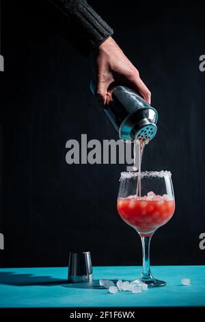 Una mano del barman che aggiunge lo sciroppo ad un cocktail con il ghiaccio Foto Stock