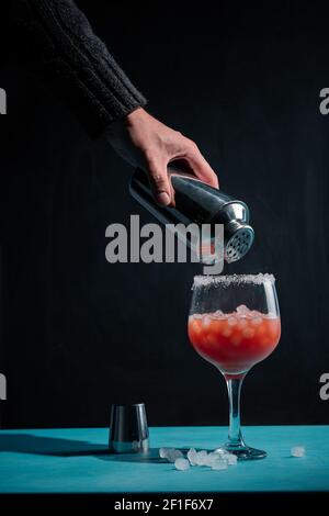 Una mano del barman che aggiunge lo sciroppo ad un cocktail con il ghiaccio Foto Stock