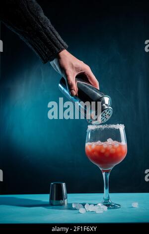 Una mano del barman che aggiunge lo sciroppo ad un cocktail con il ghiaccio Foto Stock