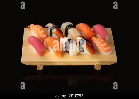 Set di sushi. Involtini con caviale rosso di anguilla di salmone e verdure su sfondo nero. Foto Stock